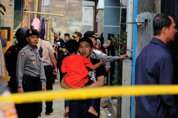 Warga melintas di tengah penjagaan polisi